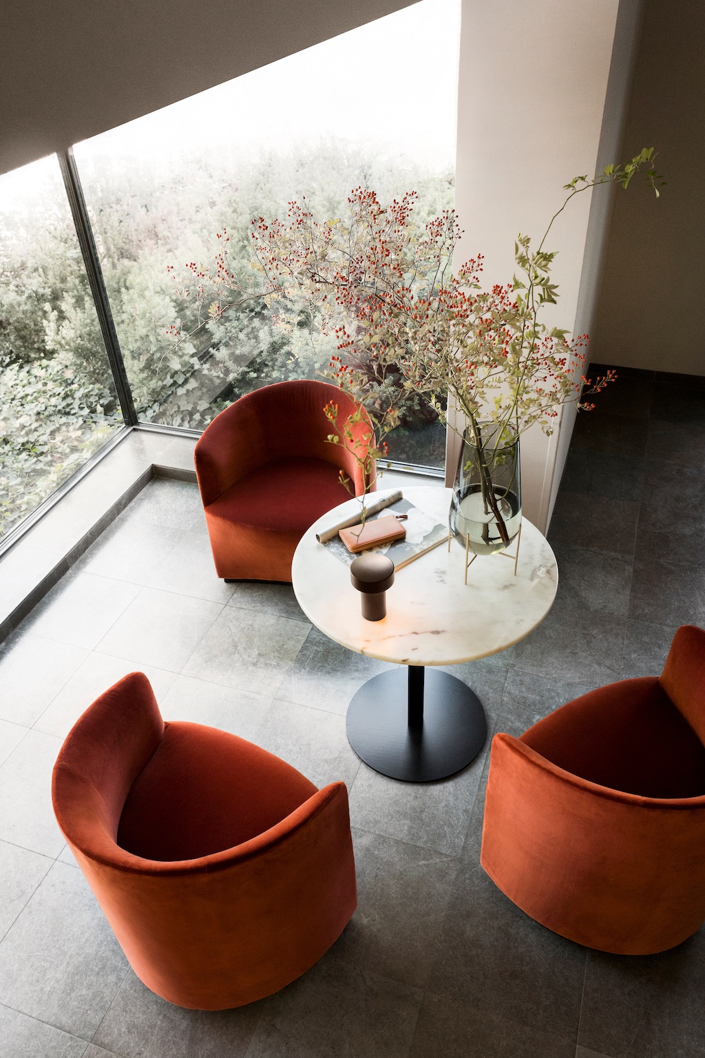 Drei Tearoom Sessel von Menu stehen um einen Bistrotisch mit Marmorplatte. Blick von schräg-oben.