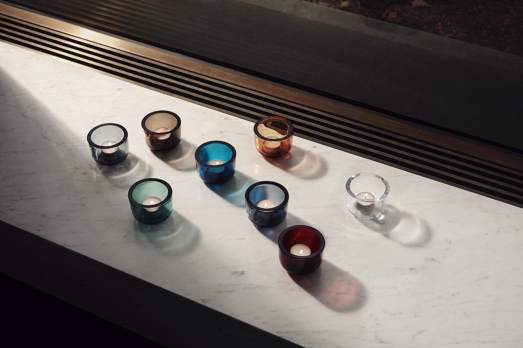 Teelichthalter von Iittale in verschiedenen Farben stehen auf Fenstersims aus Marmor. Sonnenlicht fällt drauf. 