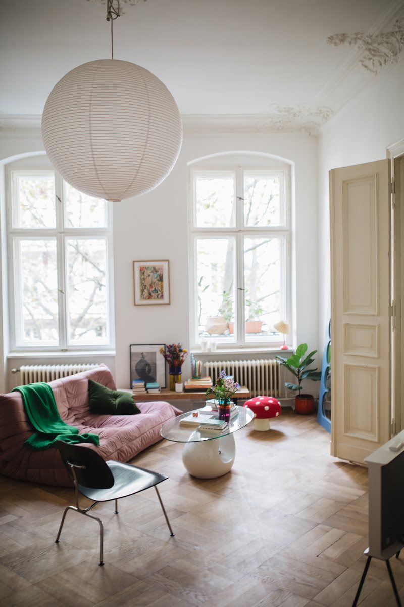 WOhnzimmer: Rosa Ligne Roset Togo Sofa, Eames Plywood Chair und Reispapierlampe an der Decke