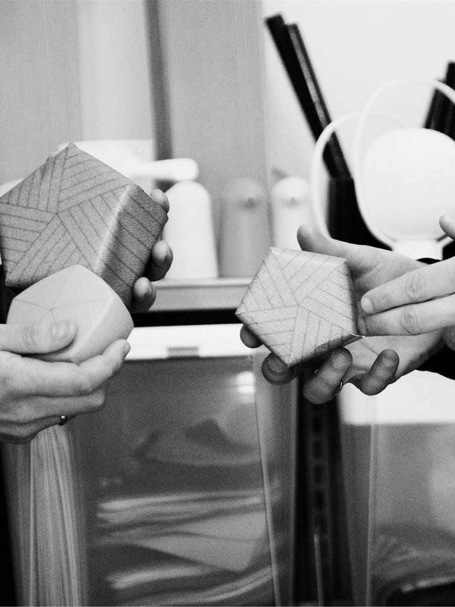 Anderssen Voll im Interview. Zwei Paar Hände halten Papiermodelle des Poufs, Foto in schwarz-weiß