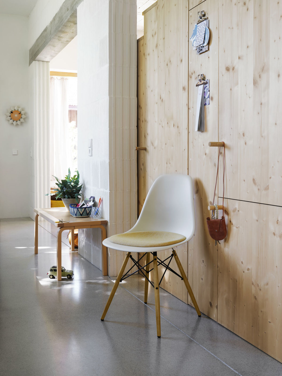 Ein Blick in die Vitra Home Stories Winter 2021/22. Eames Plastic Chair vor einem Einbauschrank aus ungebandeltem Holz. 
