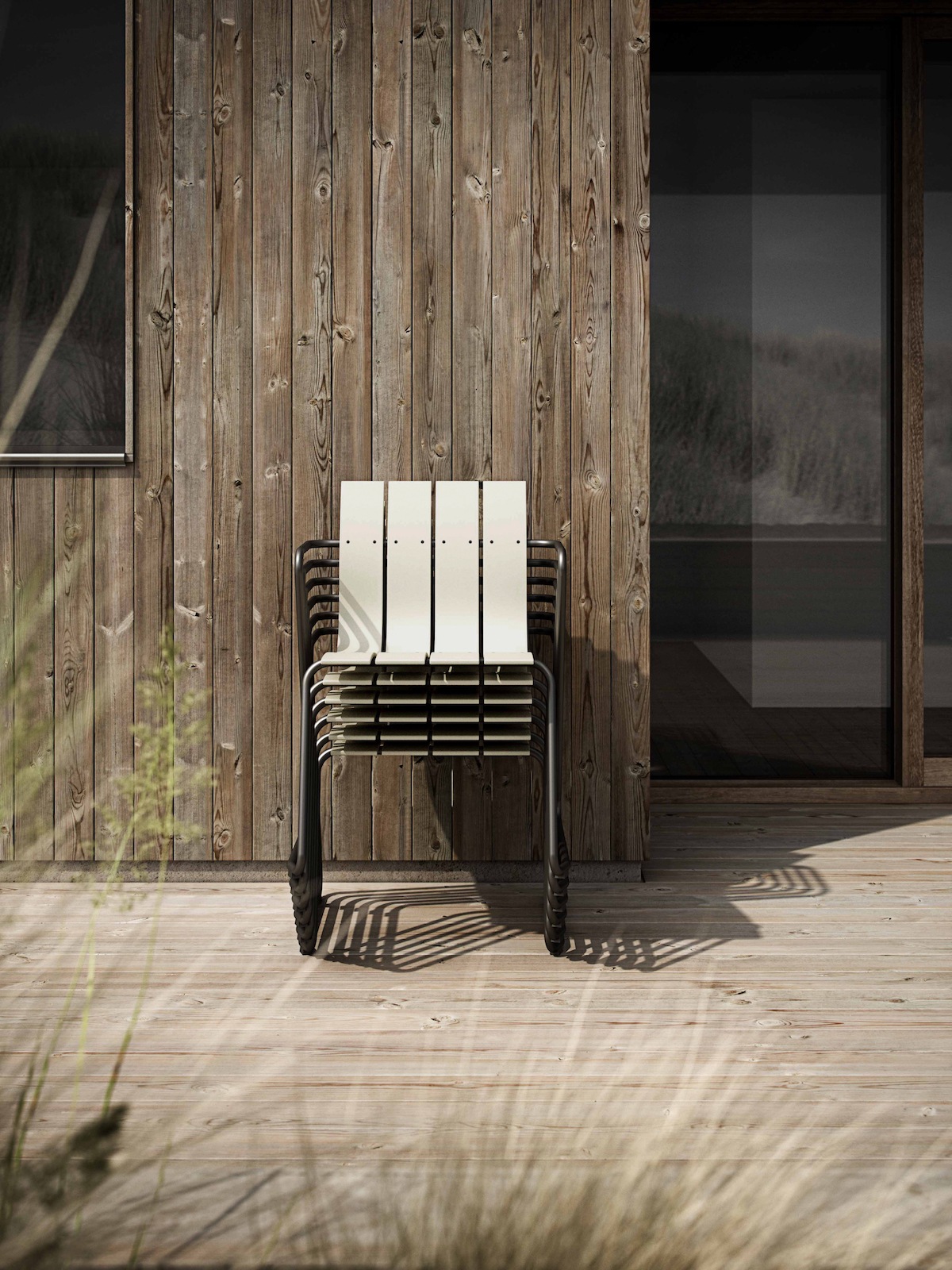 Stapel mater Ocean Stühle in Creme vor einem modernen Holzhaus
