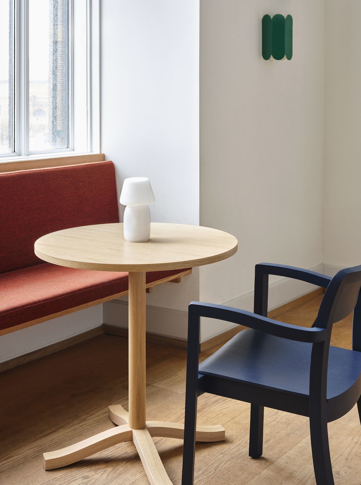 Pastis Esstisch, eine rot gepolsterte Bank und ein blauer Armlehnstuhl am Fenster. 