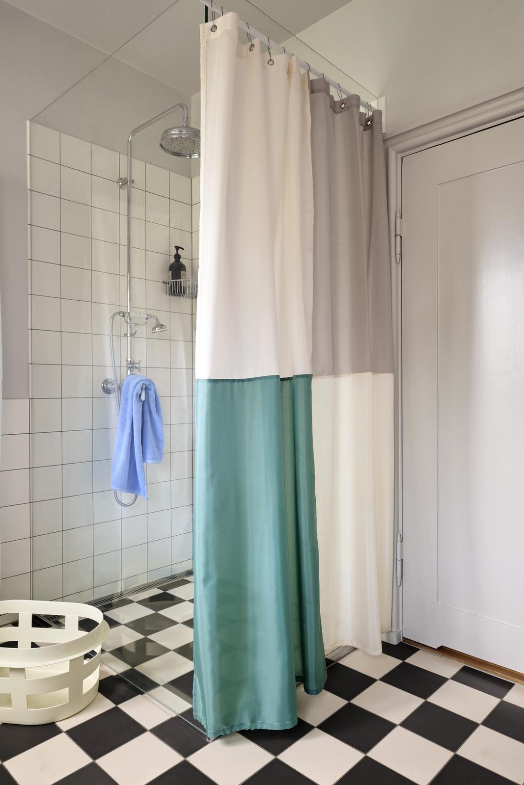 Dusche mit bunterm Duschvorhang und Fußboden im Schachbrettmuster