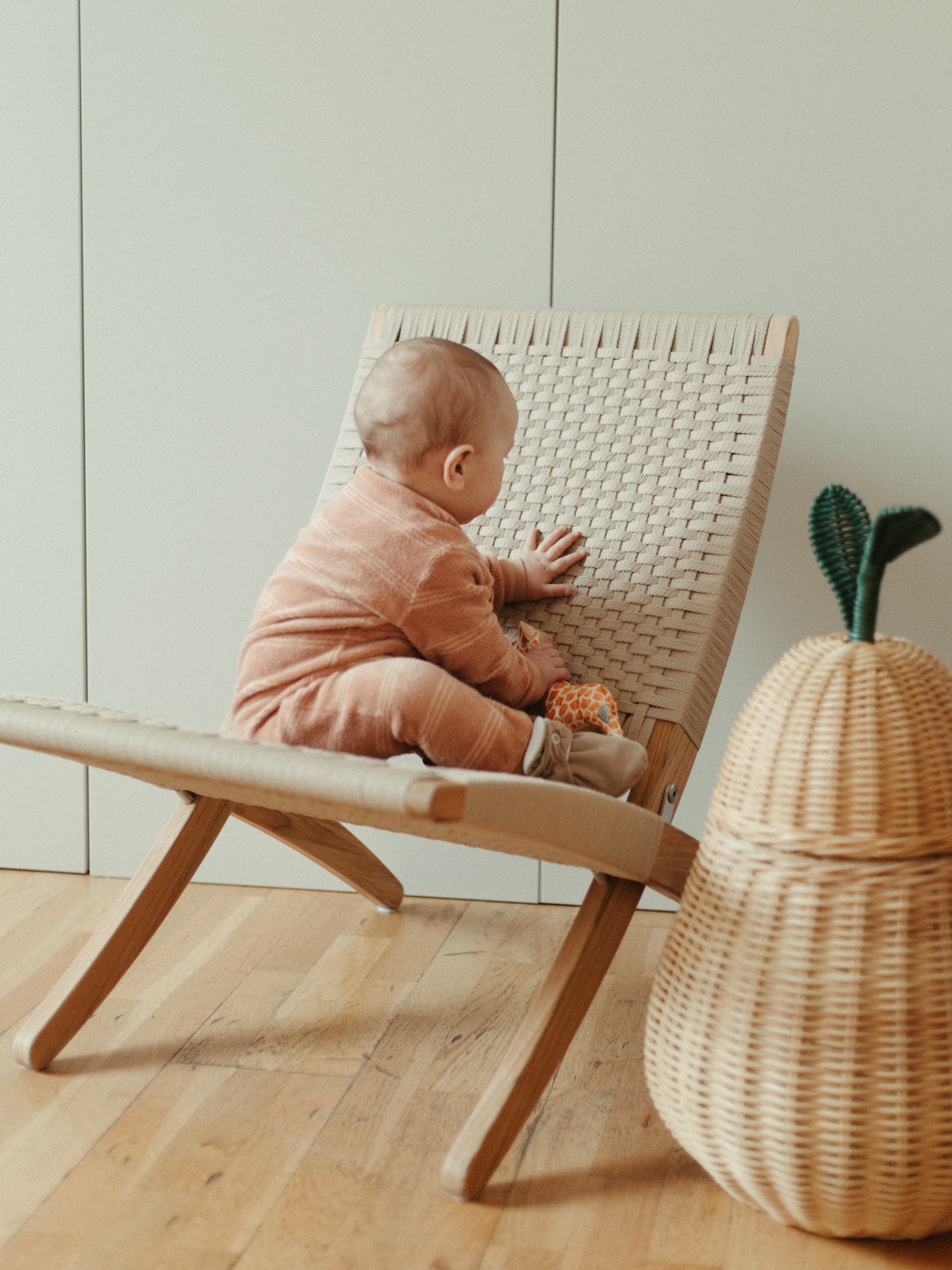 Kleinkind sitzt rücklinks auf einem mit Kordel bespanntem Klappsessel.