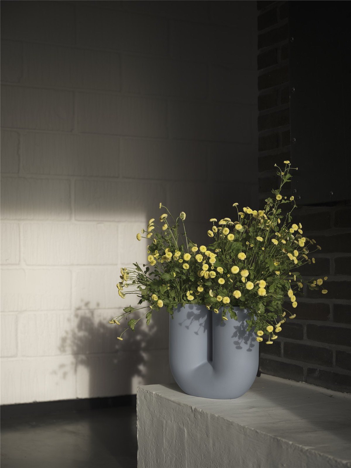 U-förmige Vase in Pastellblau mit gelben Blumen
