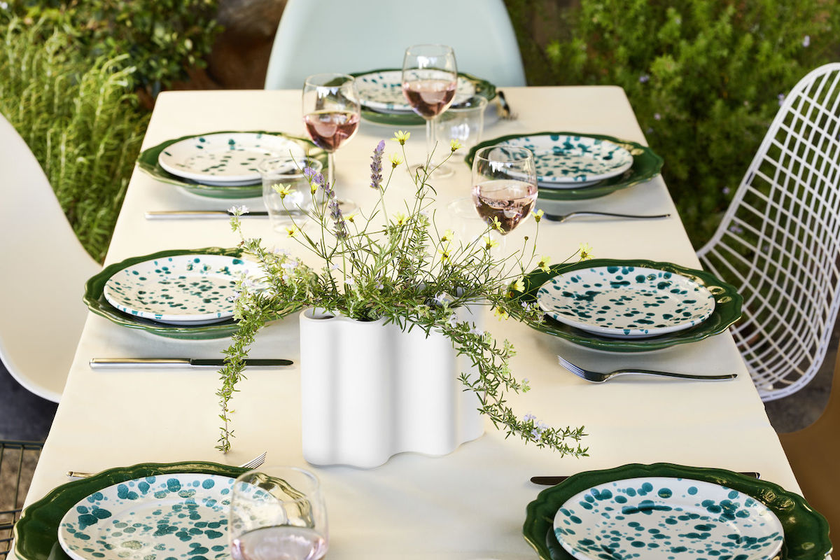 Vasenguide Mood: Esstisch eingedeckt mit gepunkteten Tellern, in der Mitte des Tisches steht eine Vase mit rankenden Thymianzweigen und Wildblumen. 