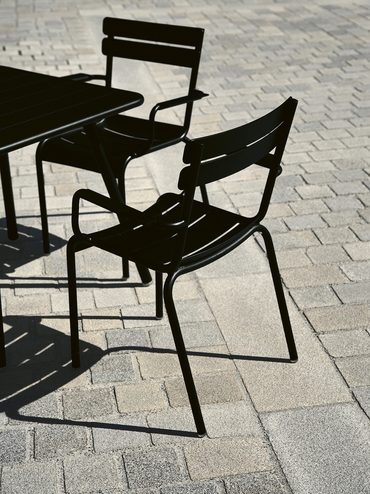 Schwarze Luxembourg Esstischsrühle von Fermob auf einem gepflasterten Platz