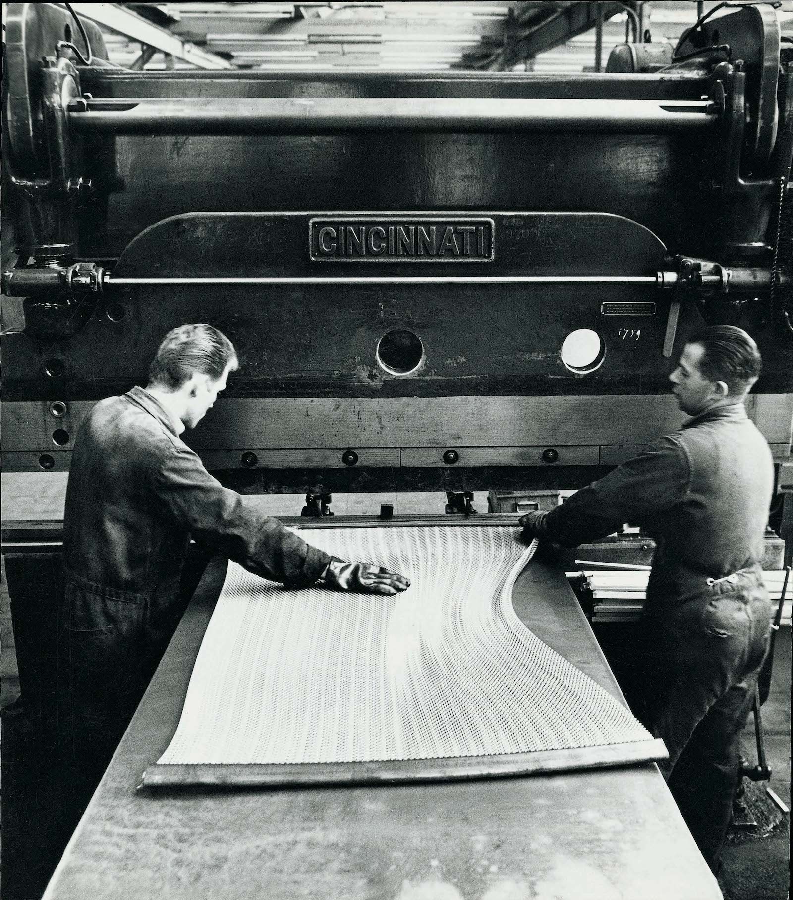 Historisches Foto der Fertigung einer Spiralmatratze mit zwei Arbeitern an einer großen Maschine
