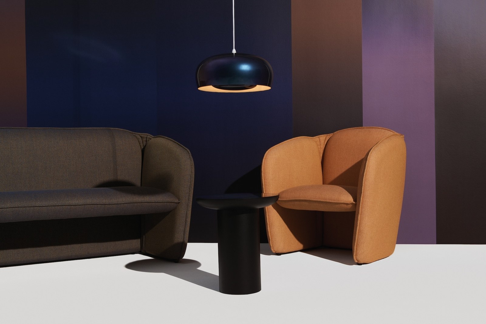 Schwarze Leuchte über einer Sitzgruppe mit Sofa, Sessel und Beistelltisch
